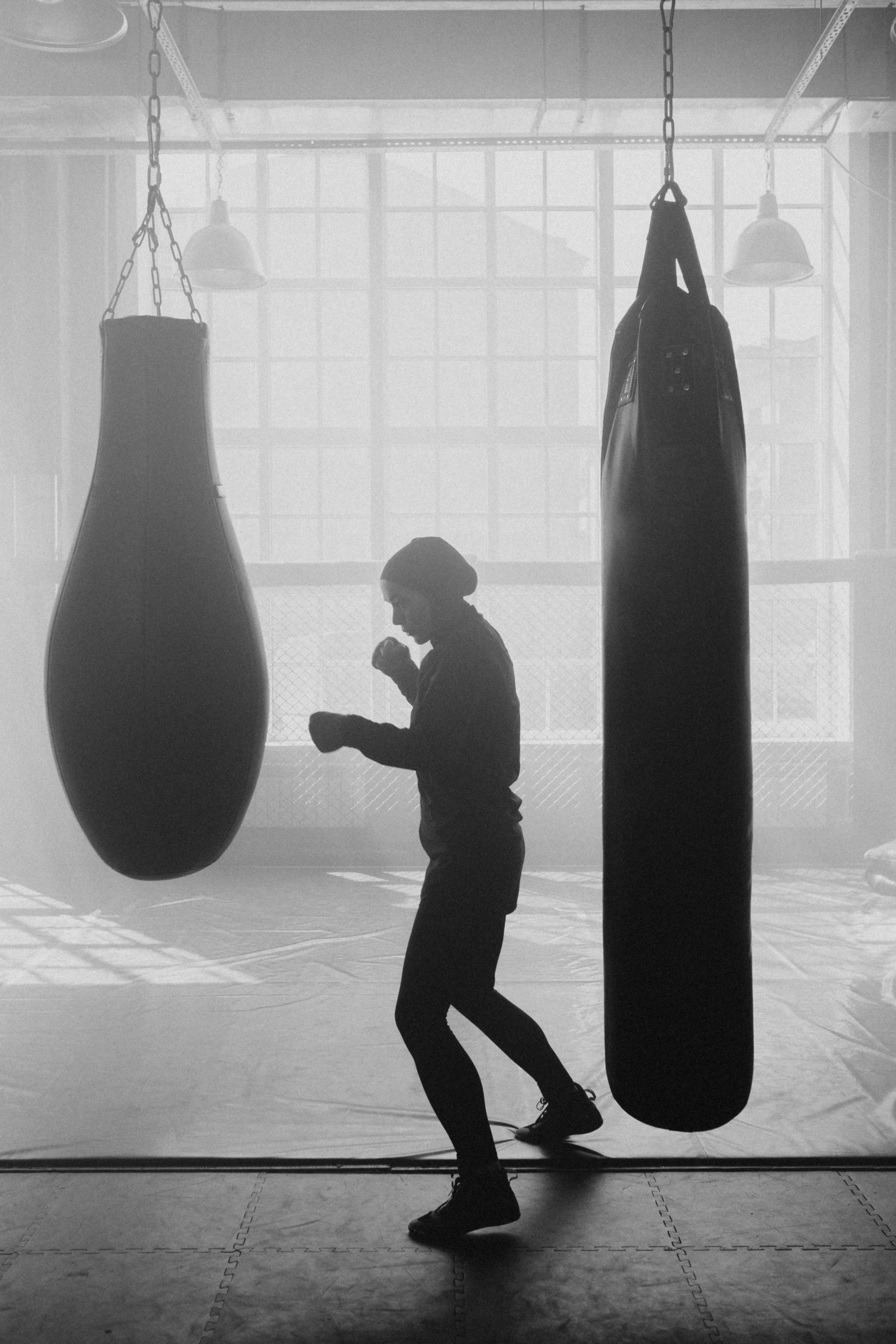 A fighter shadowboxing between heavy bags in a misty gym