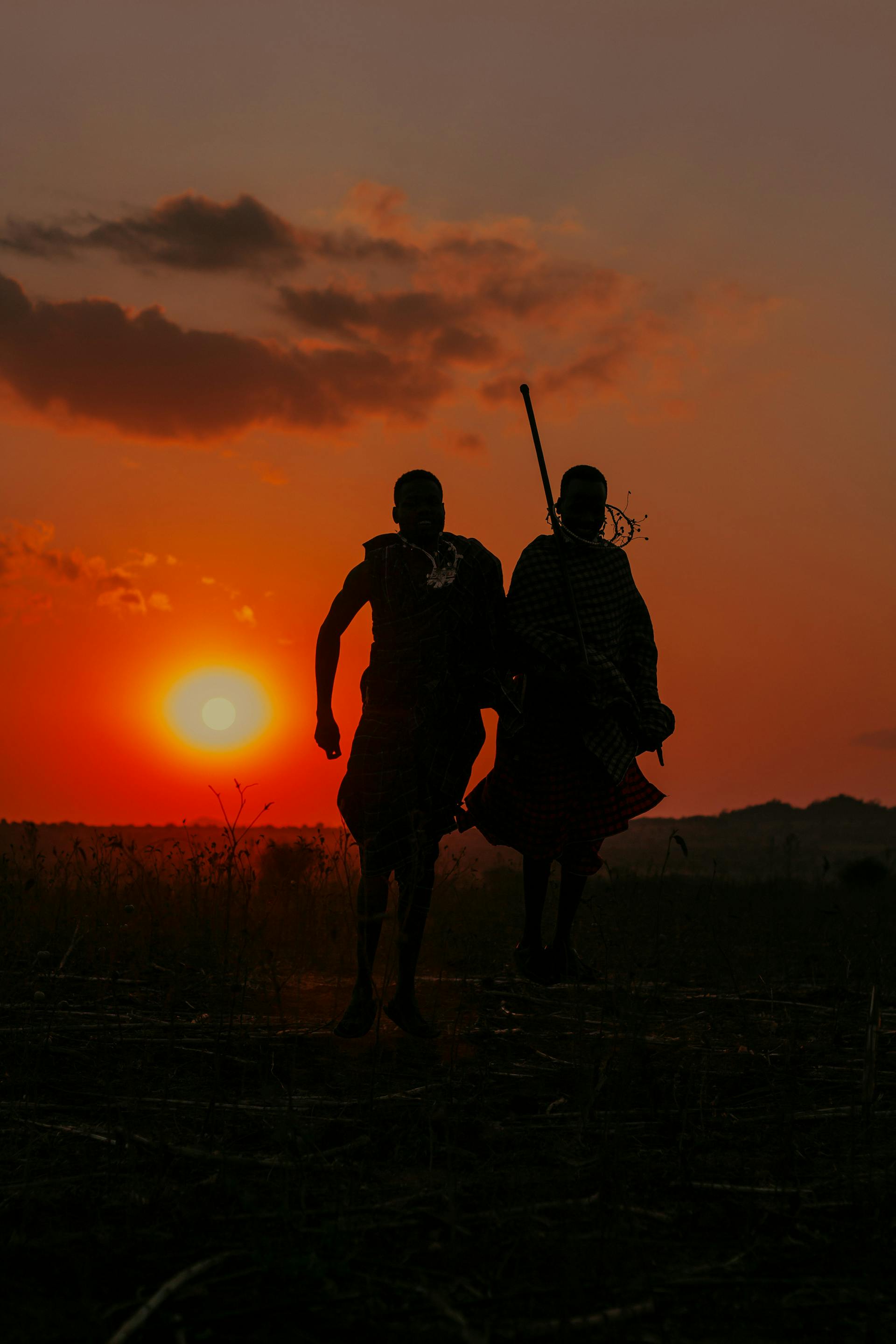 Two silhouetted figures leaping before a Tanzanian sunset