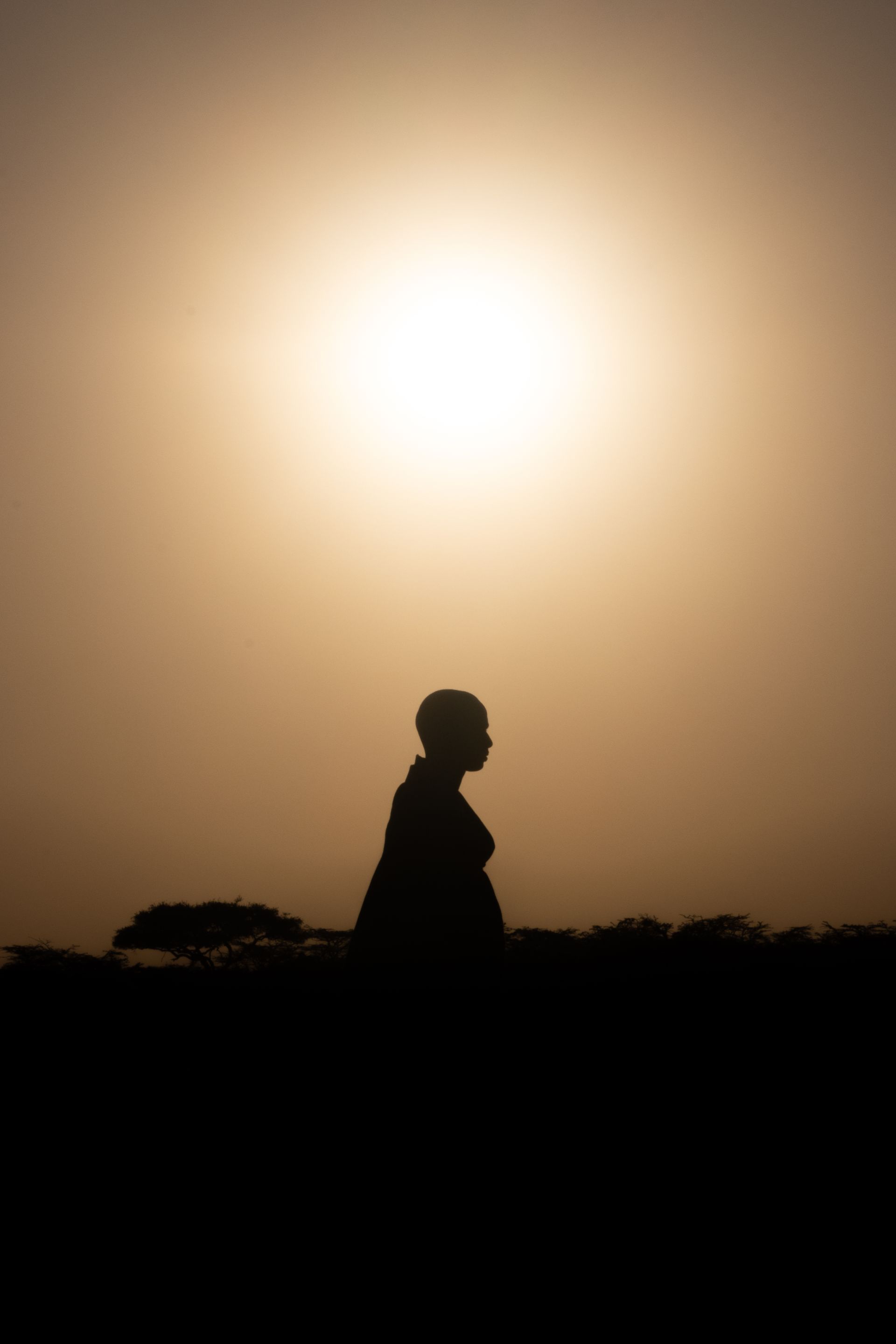 A lone figure walking beneath a dramatic sunrise sky